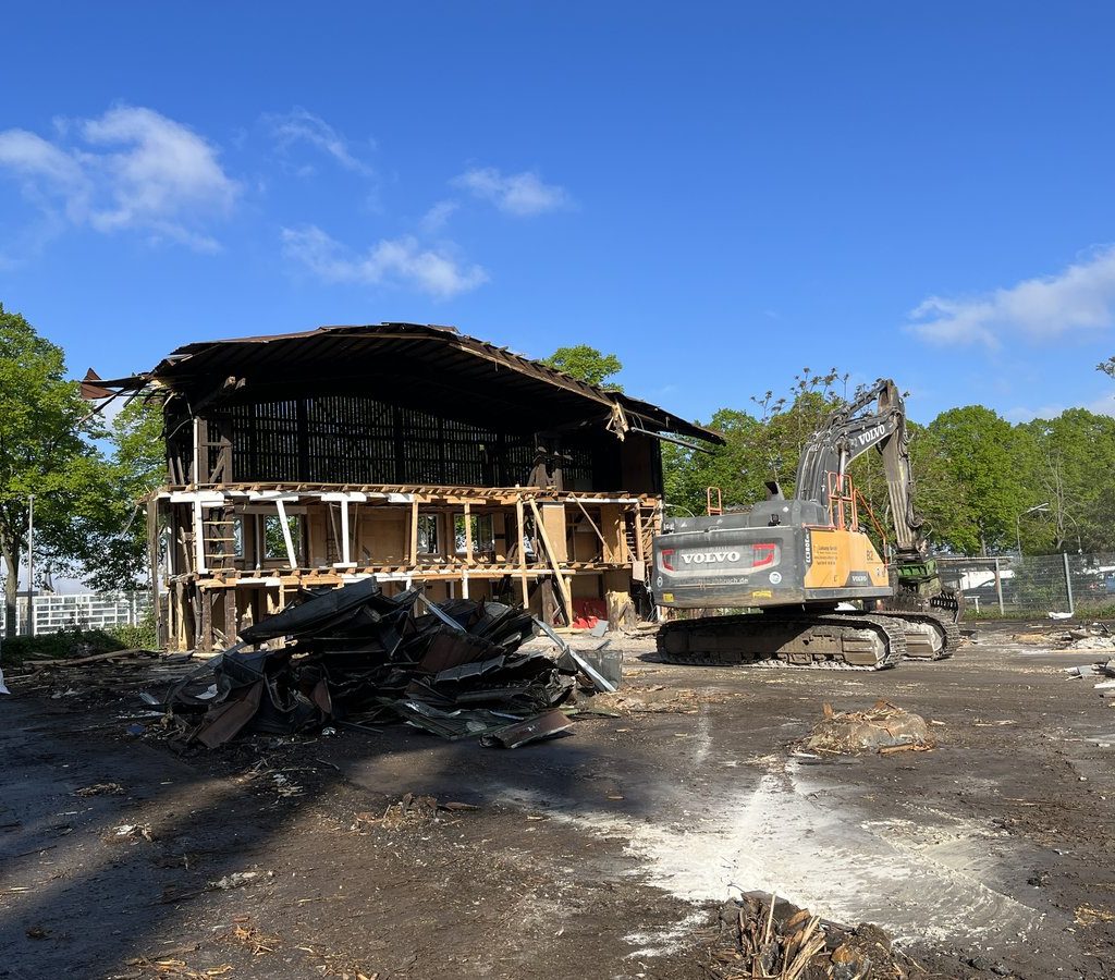 Rückbau einer ehemaligen Holzhalle im Deutzer Hafen Köln mit Bagger und Materialstapeln.