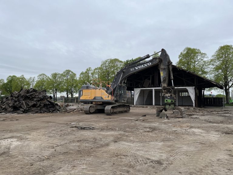 Bagger beim Rückbau der Holzhalle im Deutzer Hafen Köln, daneben gestapeltes Abbruchmaterial.