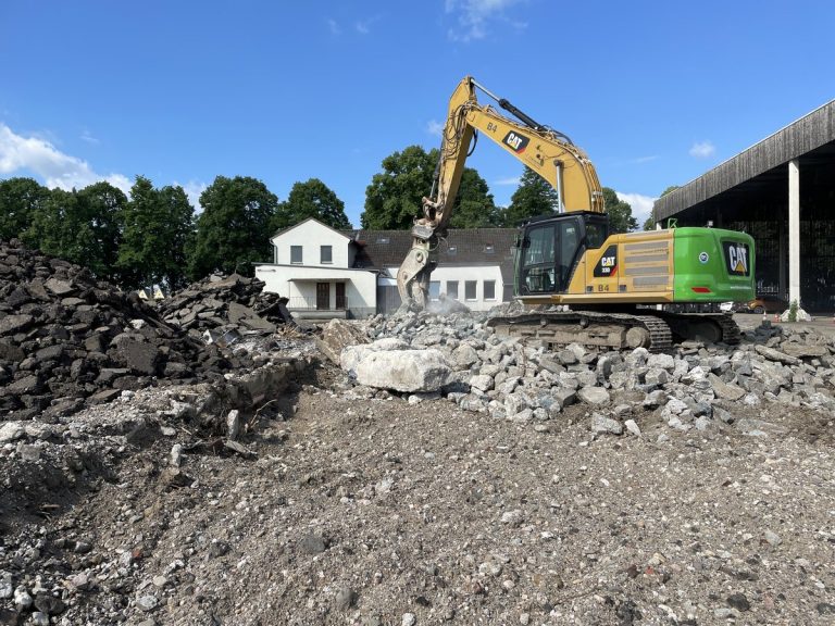 Bagger zerkleinert Betonreste beim Rückbau auf einer Fläche im Deutzer Hafen Köln.
